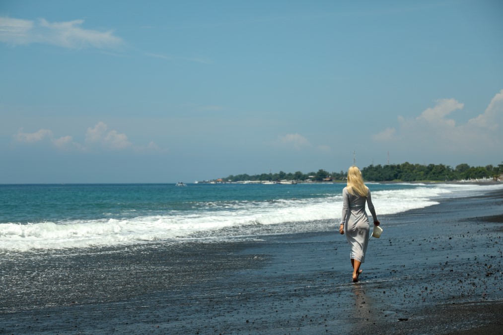 Guide francophone Bali explorant une plage de sable noir avec une voyageuse